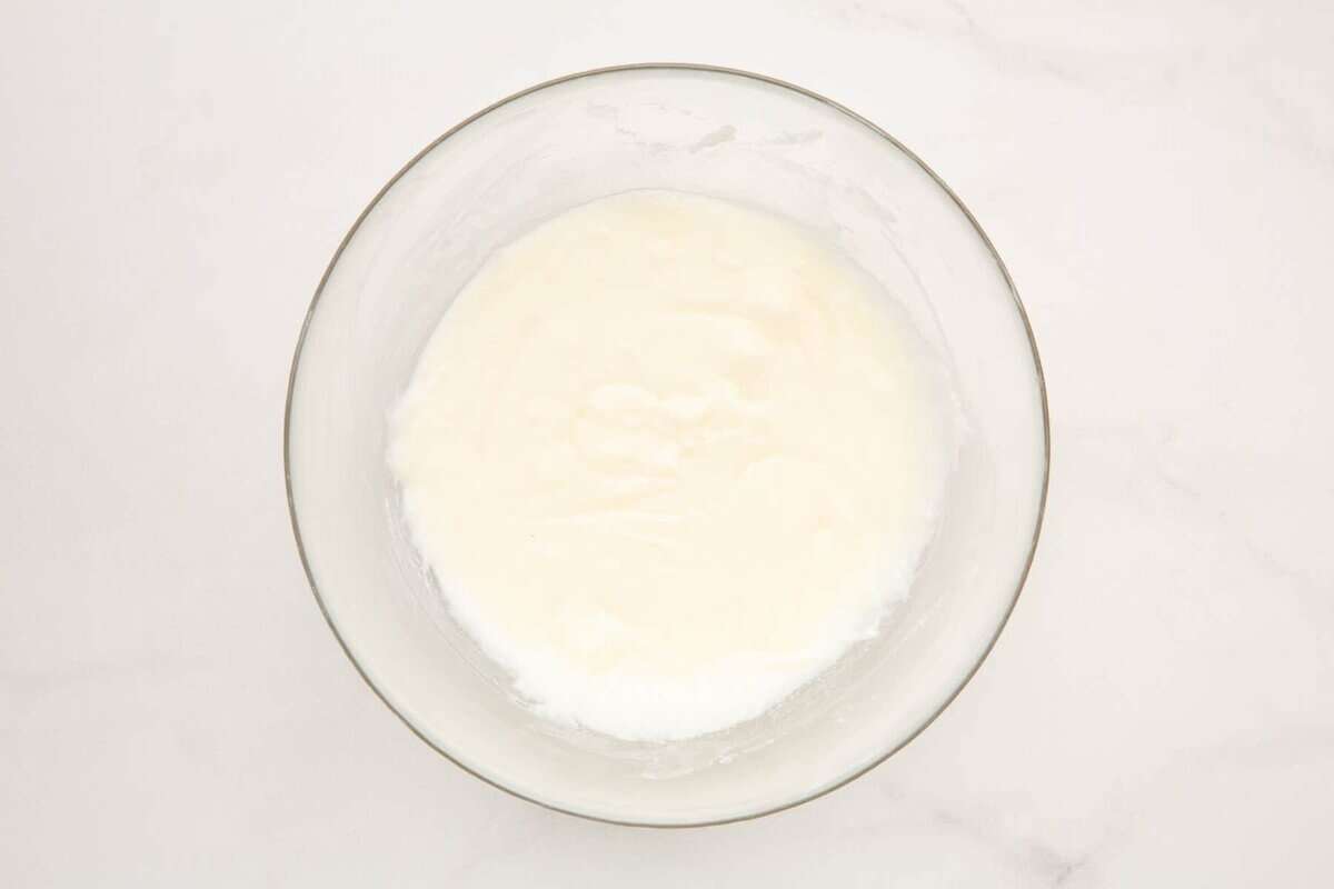 Frosting for cinnamon roll cake in bowl.