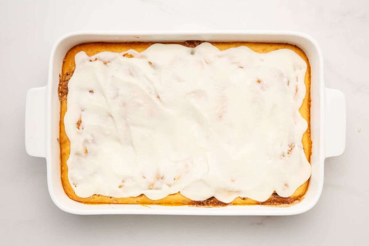 Frosted cinnamon roll cake in dish.