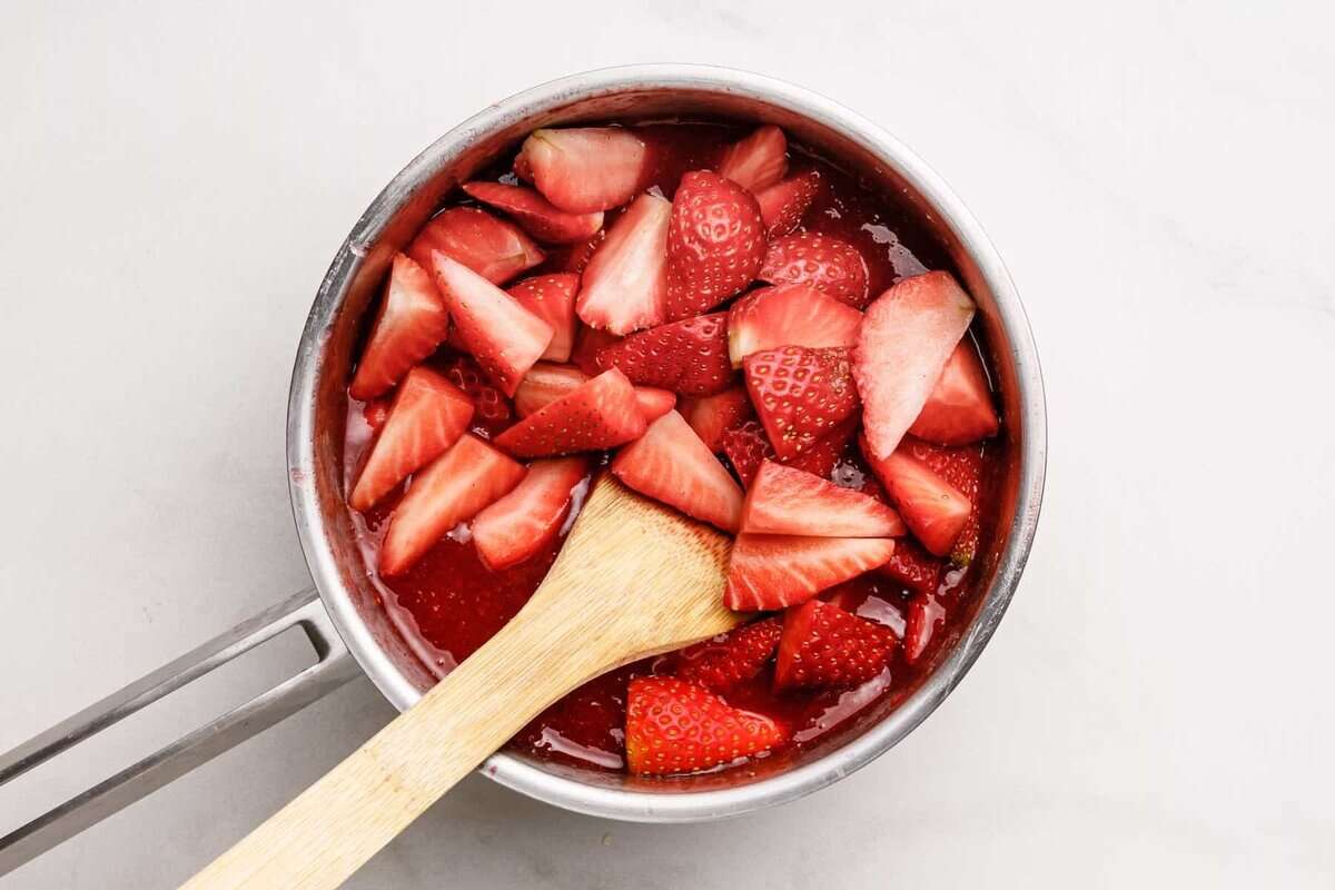 Stirring strawberries into pan for pie filling.
