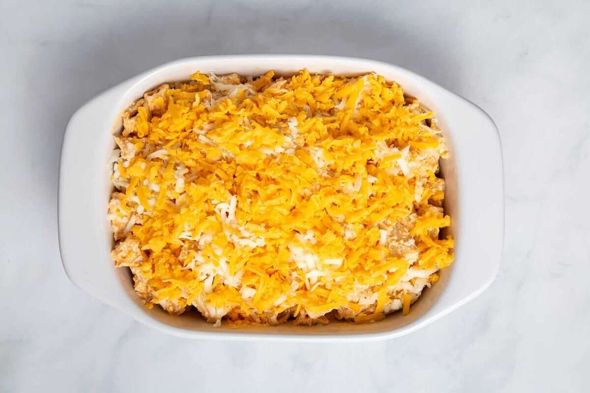 Unbaked buffalo chicken casserole with cheese sprinkled on top.