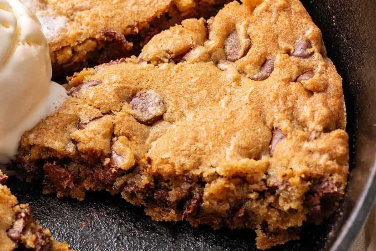 A slice of a chocolate chip cookie in a black skillet.