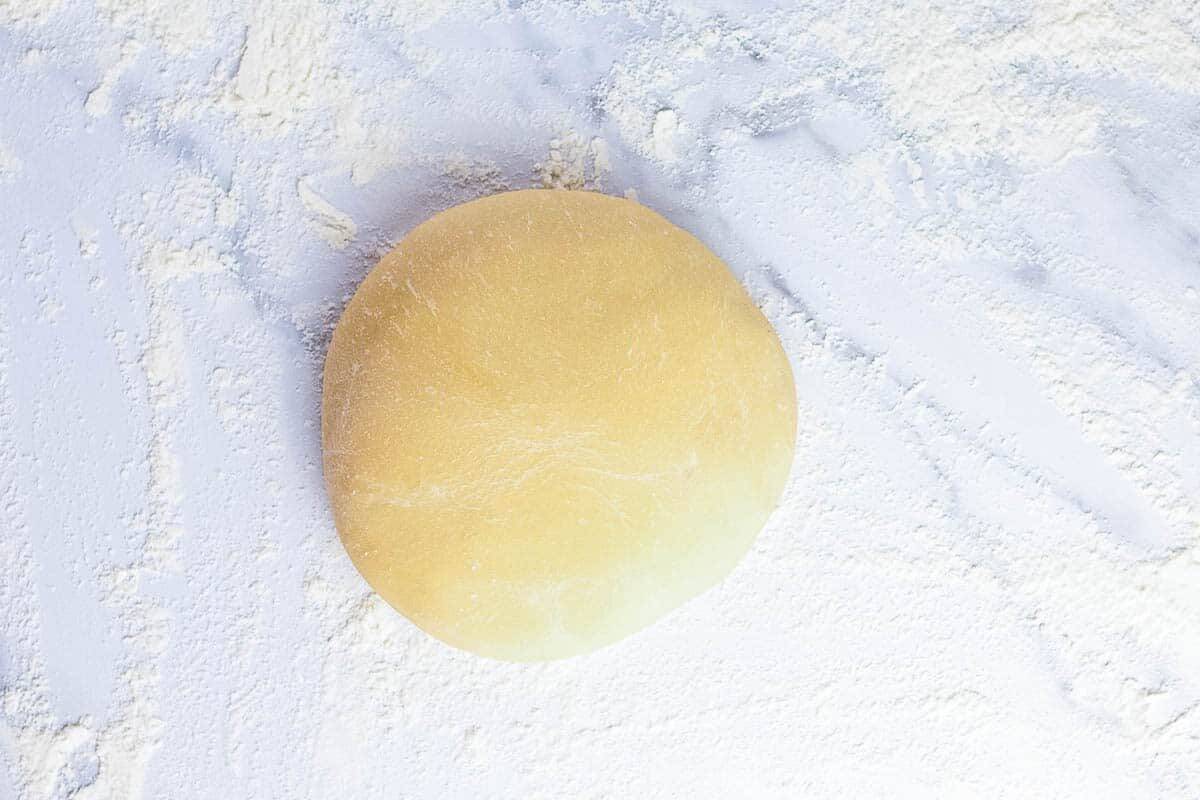 Round of french bread dough on floured marble board.