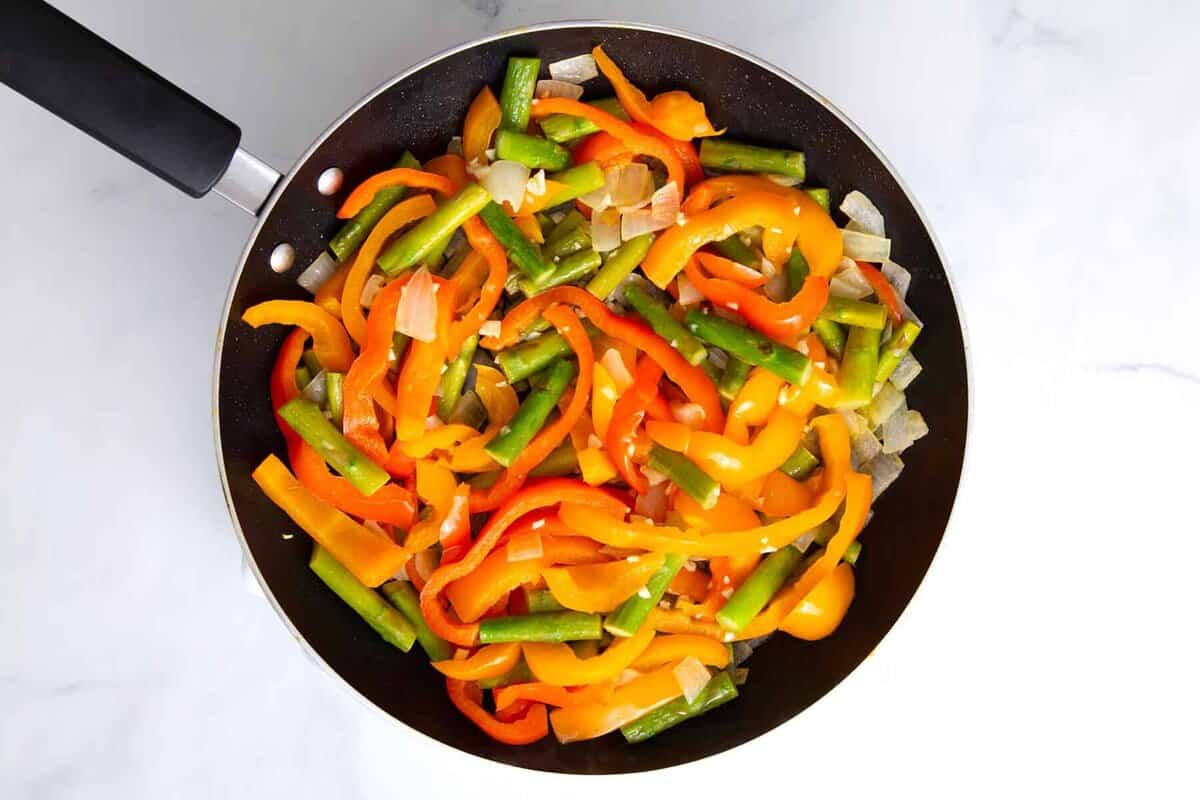 Peppers, asparagus and onions cooking in skillet.