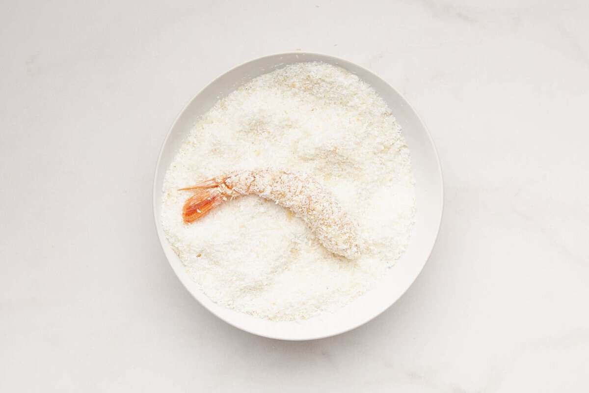 Dredging shrimp in bowl of coconut.
