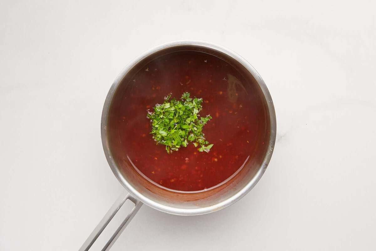 Cilantro added to pan of sweet chili sauce.