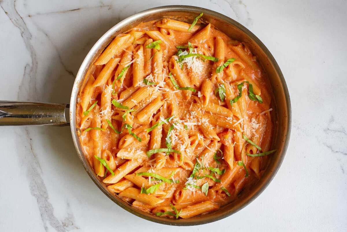 Creamy tomato pasta in skillet with basil and parmesan.
