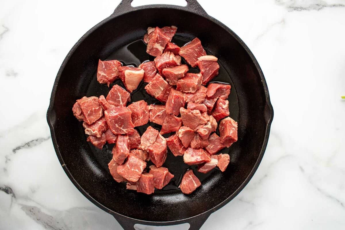 Raw steak bites in skillet.