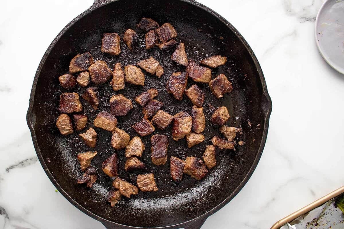 Browned steak bites in skillet.
