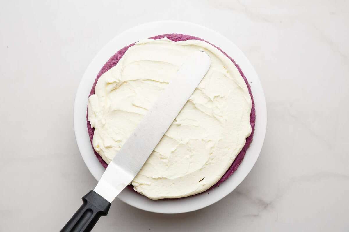Spreading buttercream over cake layer.