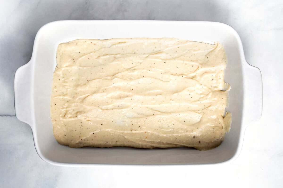 Cheese sauce spread in casserole dish.