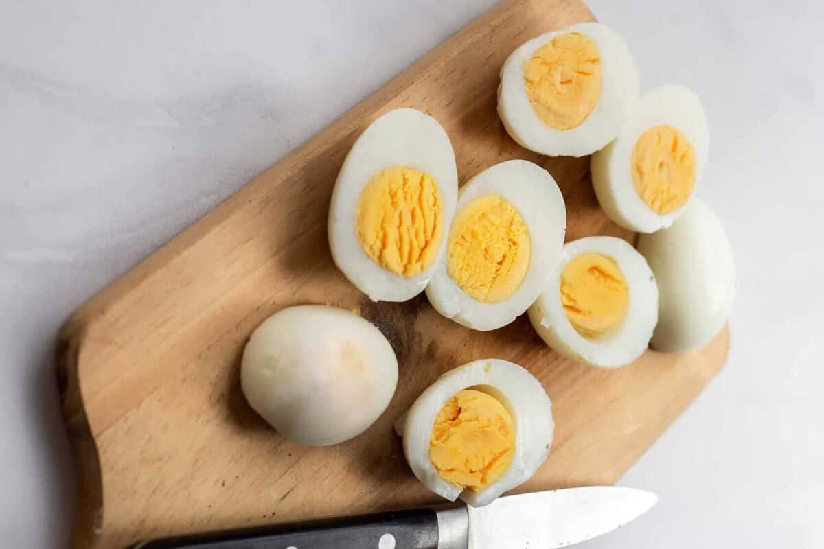 Peeled and halved hardboiled eggs on cutting board.