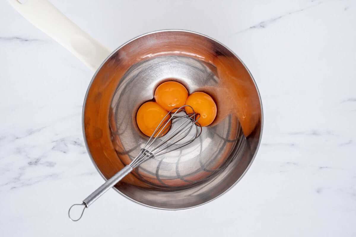 Whisking egg yolks in pan.