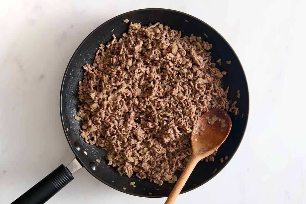 Ground beef cooking in skillet.