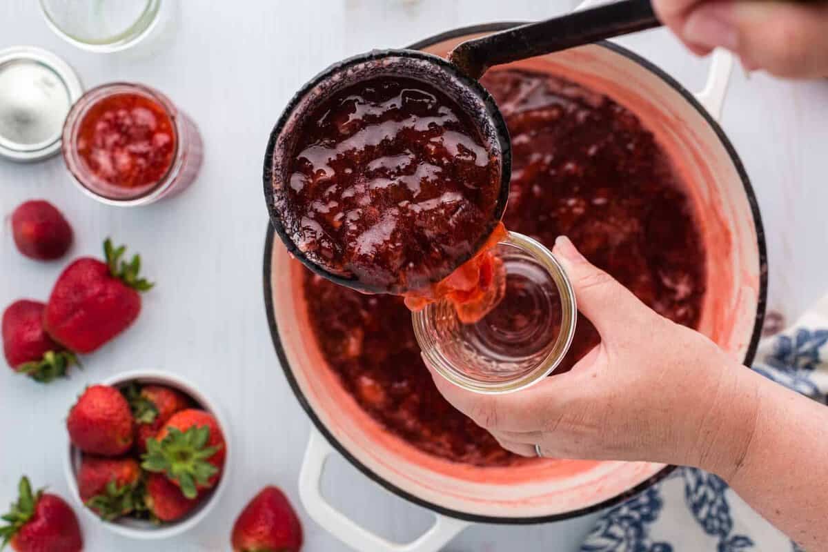 Ladling strawberry rhubarb jam into jar.