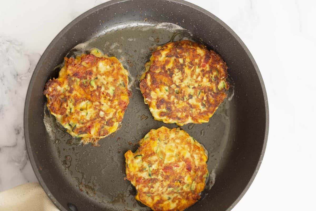 Zucchini corn fritters in skillet.