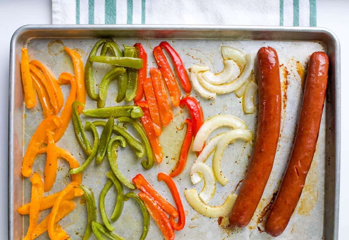 Roasted bell peppers, onions, and sausages on sheet pan.