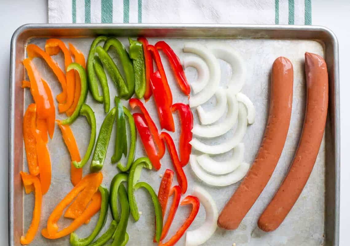 Bell peppers, onions, and sausages on sheet pan.