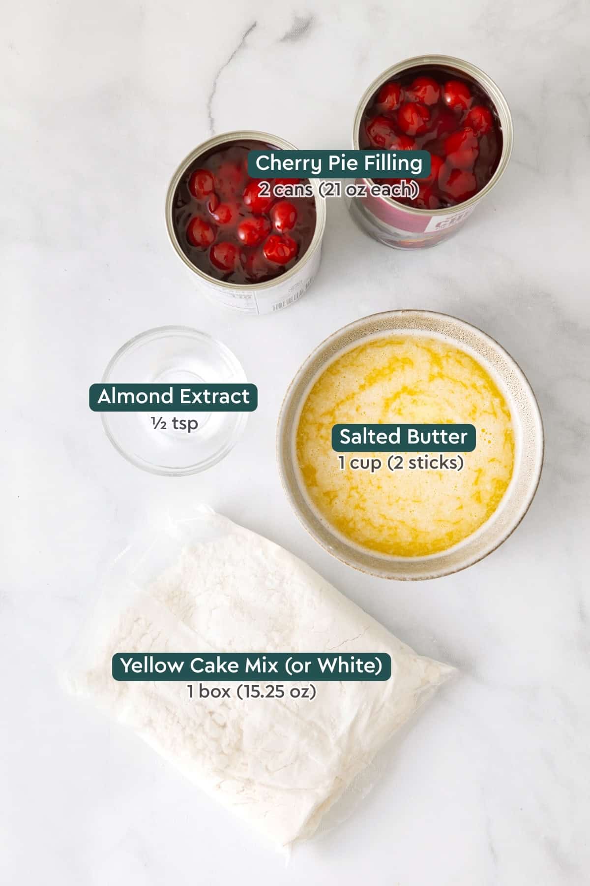 Ingredients for cherry dump cake, including cherry pie filling, almond extract, salted butter, and yellow cake mix.