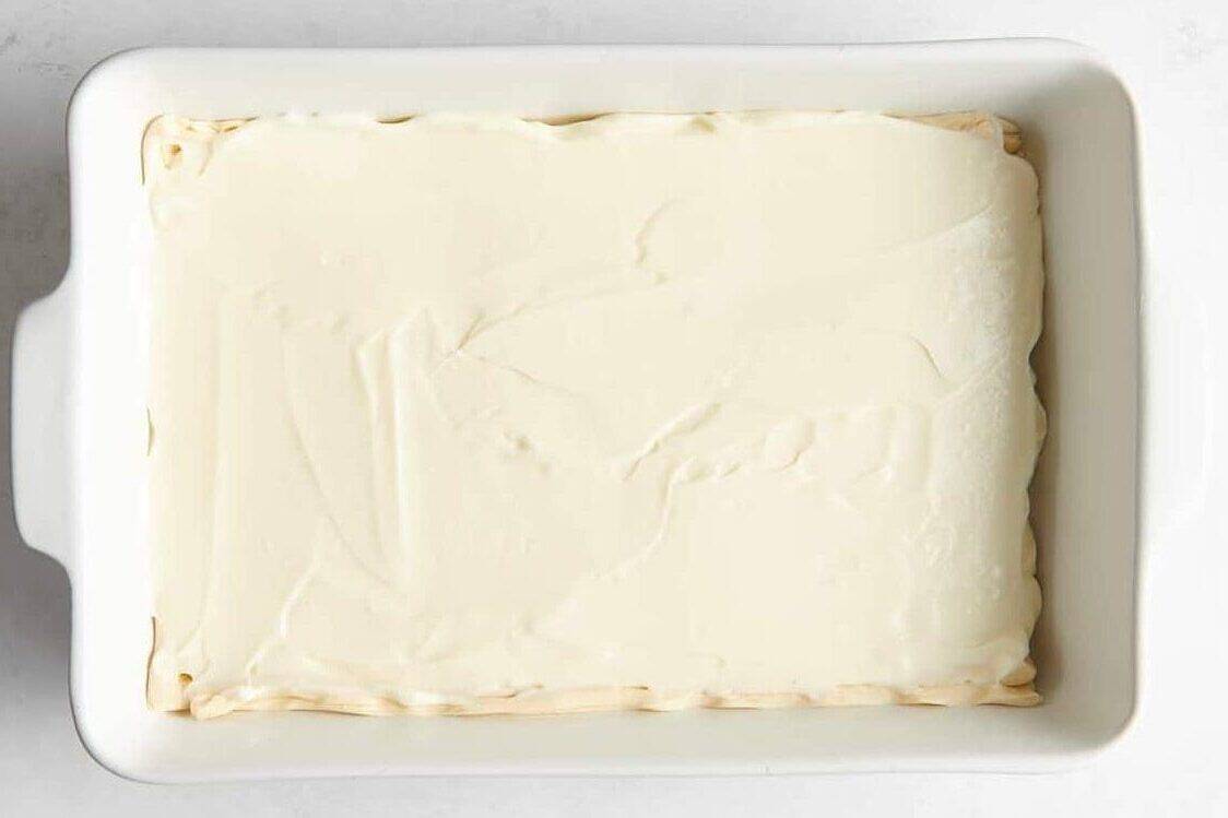 Cream cheese filling spread over crescent roll dough.