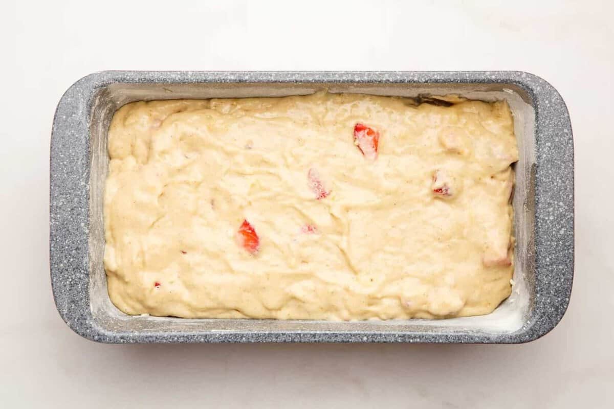 Unbaked banana bread with strawberries in loaf pan.