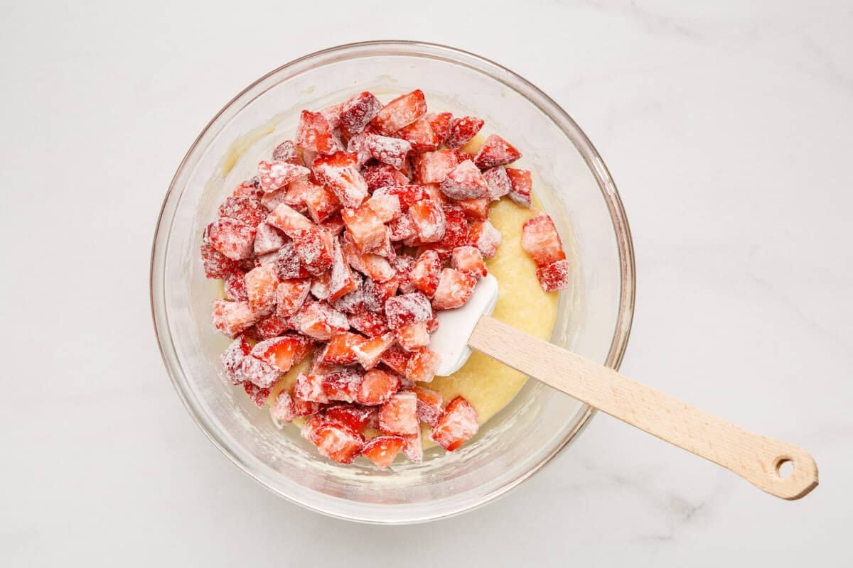 Stirring strawberries into bread batter.