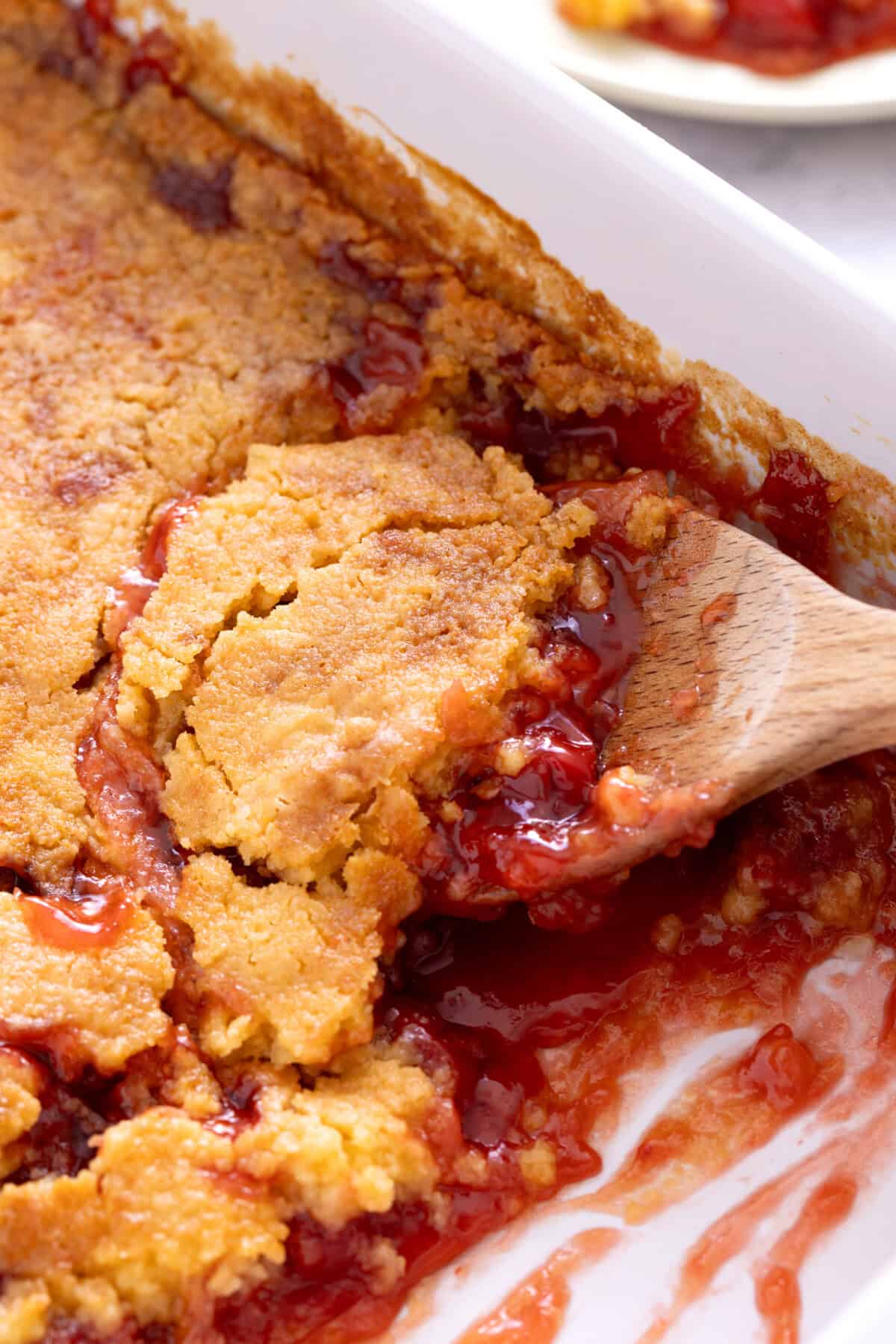 Spoon scooping cherry dump cake from pan.