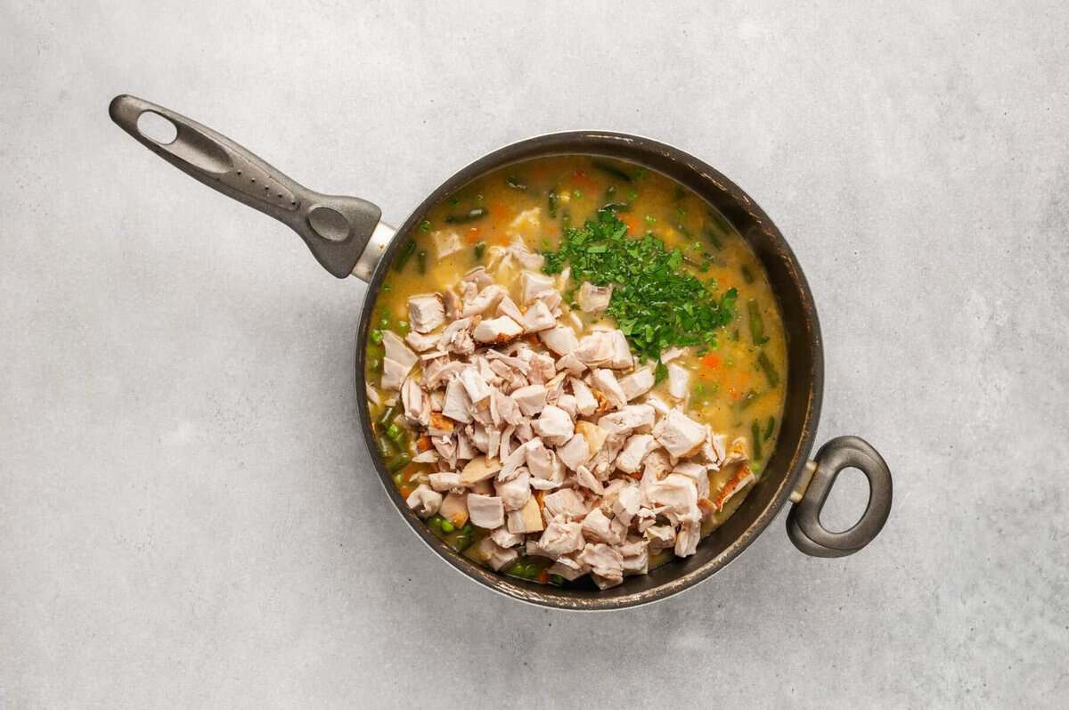 Chicken and parsley in skillet with pot pie filling.
