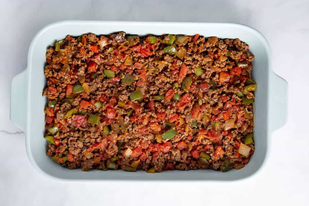 Taco and vegetable mixture layered in baking dish.