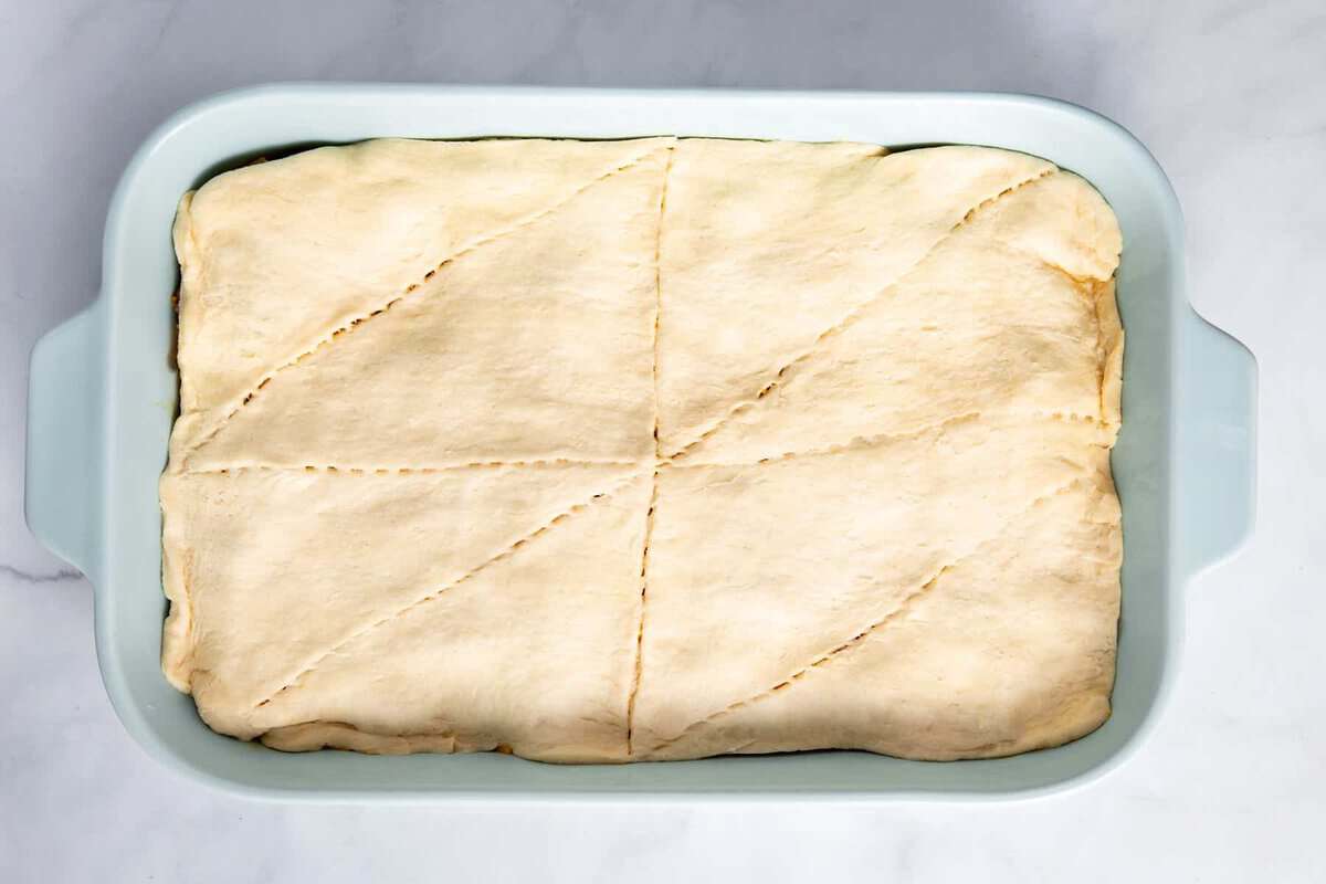 Taco bake with crescent roll dough before baking.