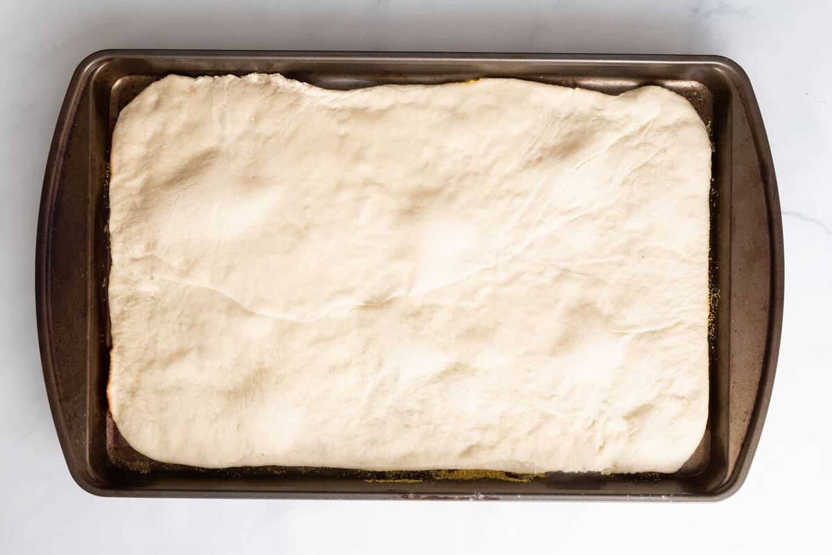 Pizza dough stretched in sheet pan.