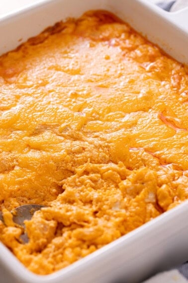 Buffalo chicken dip topped with melted cheddar in a white baking dish.
