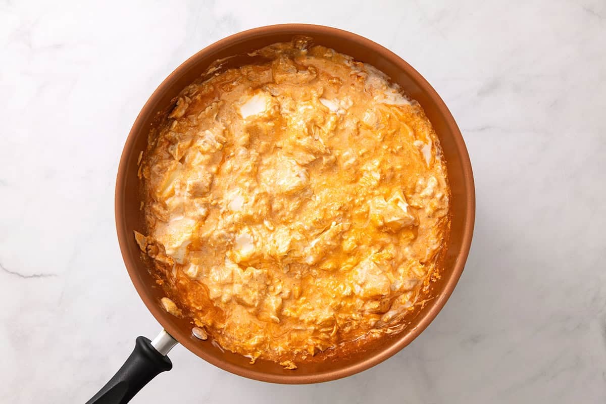 Cream cheese and ranch being stirred into buffalo chicken.