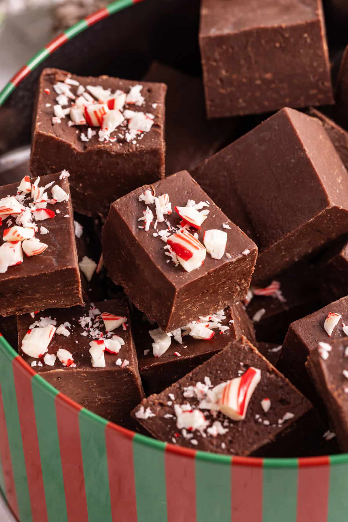 Squares of peppermint 3-ingredient fudge in candy tin.